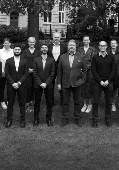 Black and white photo of the CHC Global team, standing outside. All facing the camera and smiling.